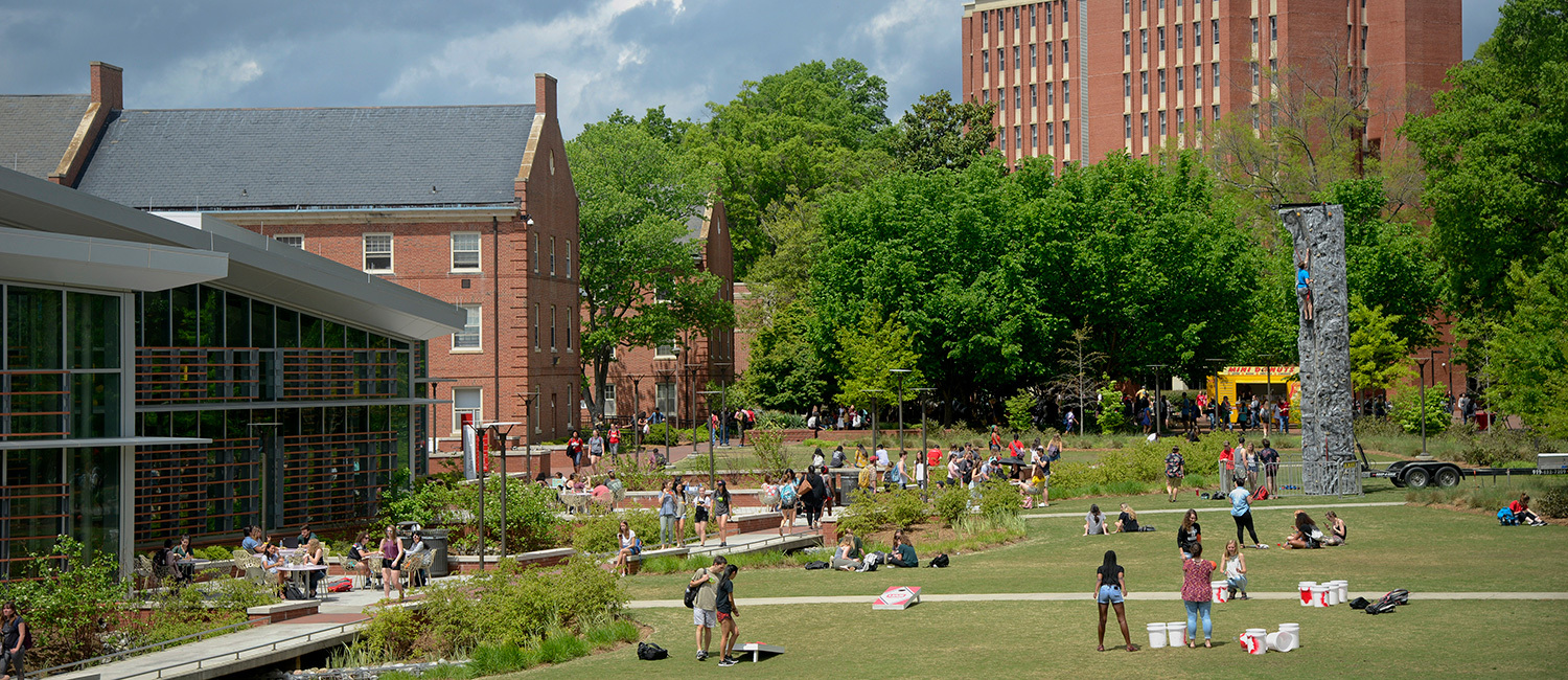 Students walk across Stafford Commons on a bright day.