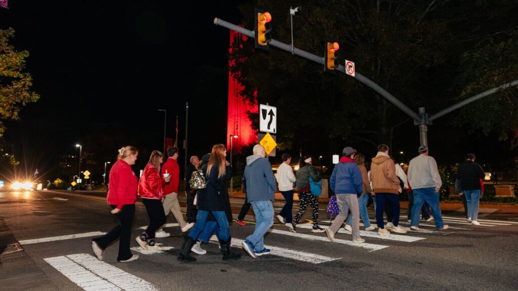 group crossing the street infront of red bell tower